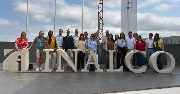 Groupe de personnes posant ensemble devant le logo en béton d'INALCO, à l'extérieur, avec un ciel partiellement nuageux.