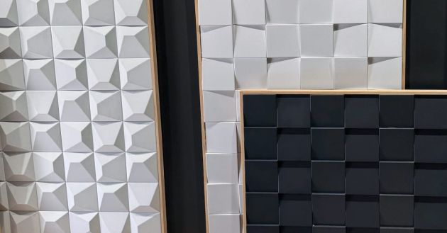 Panneaux en relief composés de formes géométriques, deux panneaux blancs avec des motifs en relief et un panneau noir avec une texture carrée.