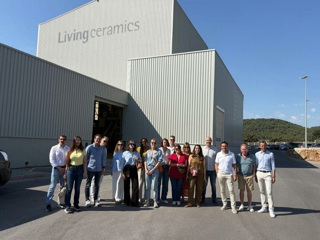 Groupe de treize personnes posant devant un bâtiment en métal avec l'inscription "Living ceramics" sur le mur.
