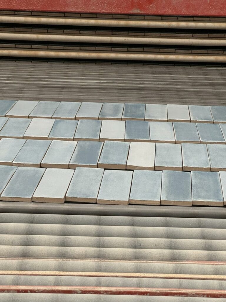 Des tuiles de couleur grise disposées en motifs sur une surface plane, avec une couche de tuiles plus claires et une surface de fond plus foncée.