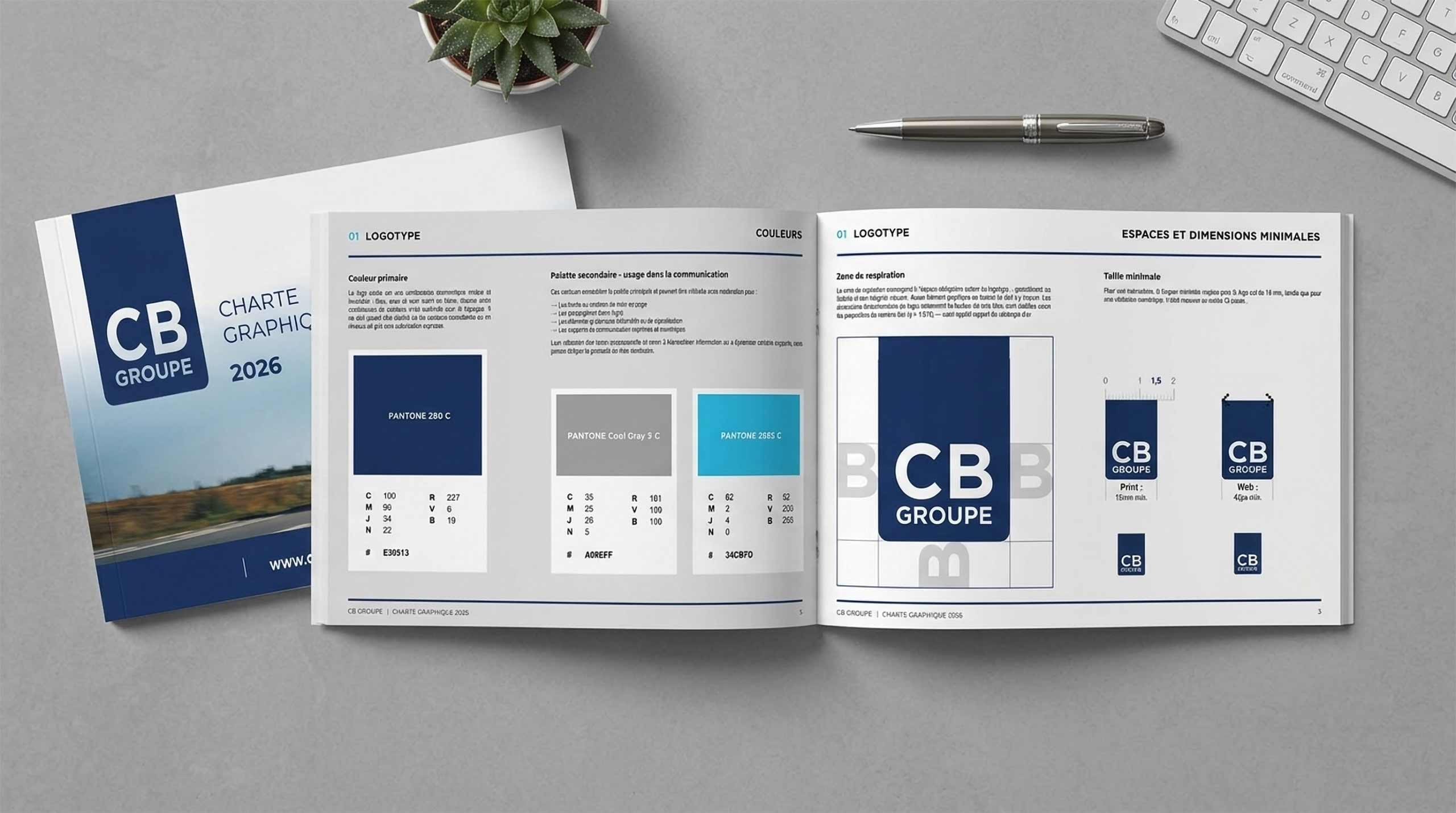 Brochure ouverte de CB Group avec guide d’identité visuelle et maquettes de logo sur un bureau gris.