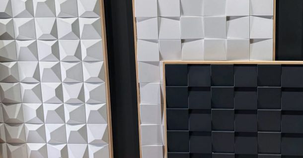 Panneaux en relief composés de formes géométriques, deux panneaux blancs avec des motifs en relief et un panneau noir avec une texture carrée.